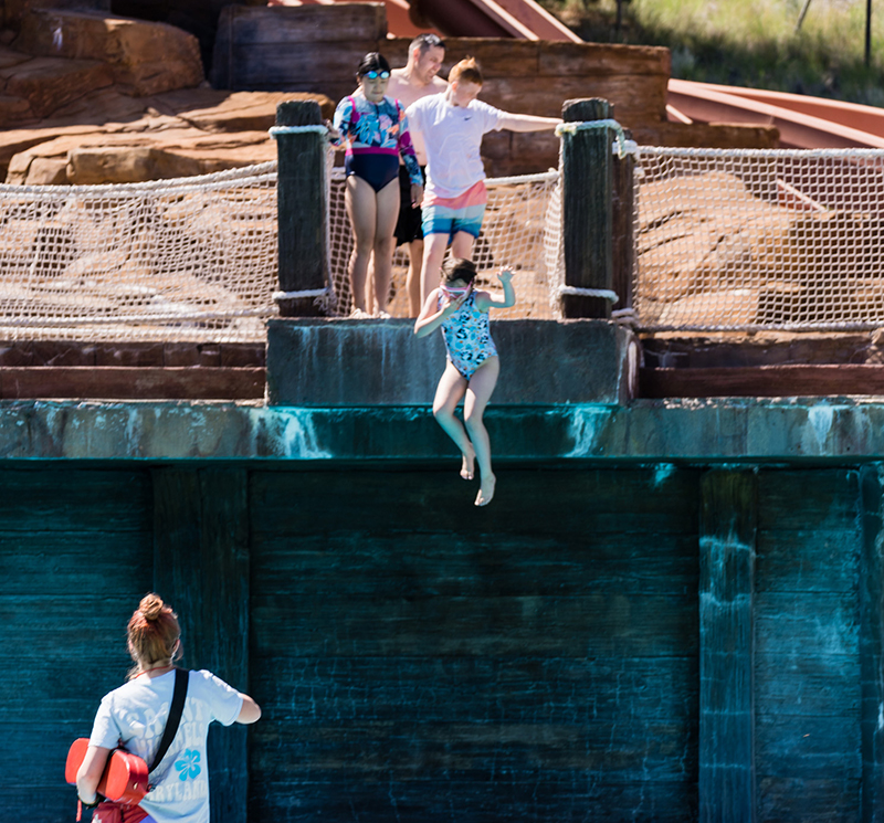 Alex Parris acting as a lifeguard while attendees of flok Family Camp West jump into a pool.