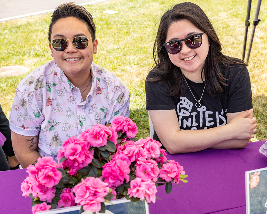 Two BioMarin employees celebrate AANHPI Heritage Month at a table with pink flowers
