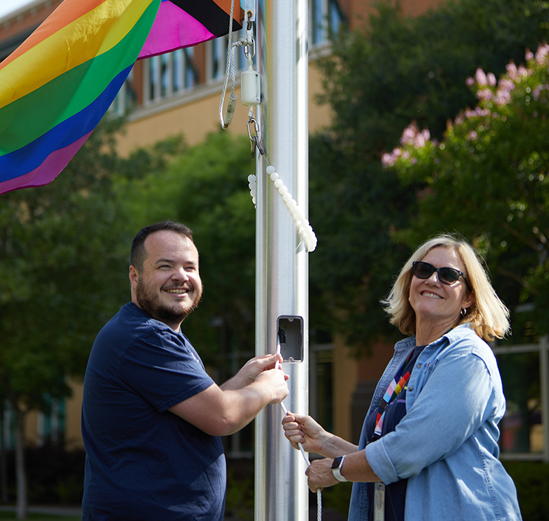 Two BioMarin employees raise the Pride flag at the company's San Rafael campus.