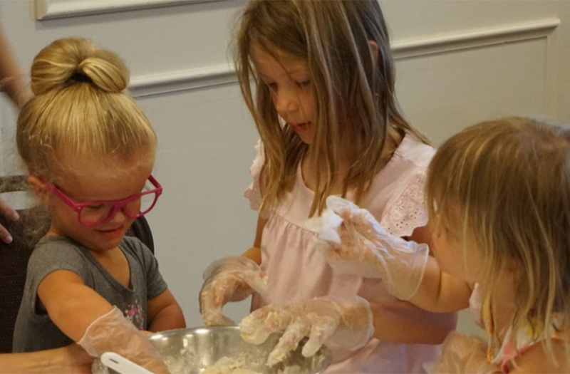 Three children making bread at Rising Love event hosted by The Chandler Project