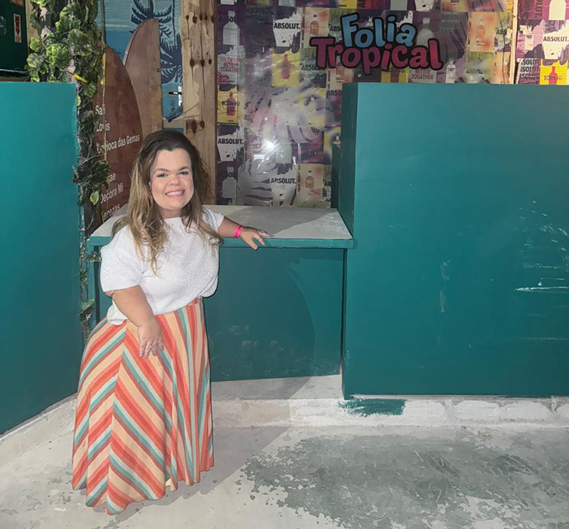 Rebeca Costa standing in front of a lowered bar counter constructed for Carnival